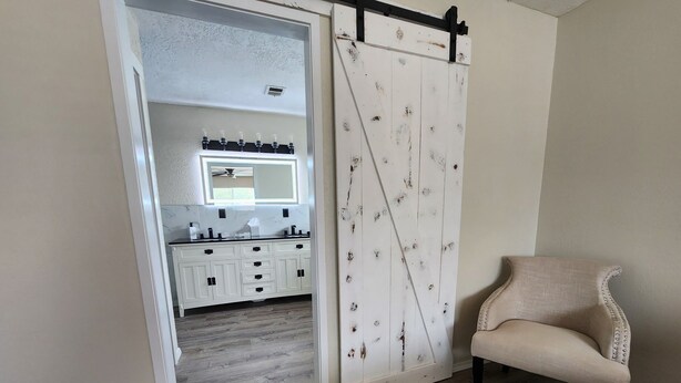 Ein Zimmer mit einer Schiebetür zu einem Badezimmer, einem Sessel und einem Holzboden.
