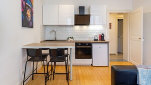 A modern kitchen with white cabinets, a wooden countertop, and a small island with two black chairs.
