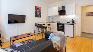 A compact living space with a kitchenette, a flat-screen TV, a sofa, and a dining area.