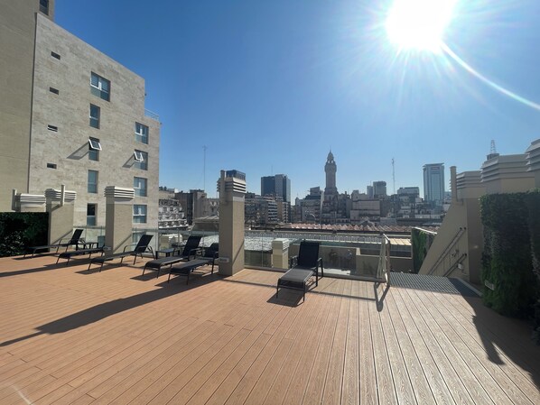 A rooftop terrace with lounge chairs and a view of the city skyline.