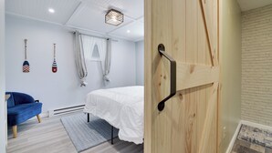 A bedroom with a bed, a blue chair, and two paddleboards on the wall.