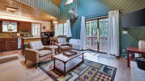 A spacious living area with a large window, a mounted deer head, and a cozy seating arrangement.