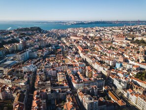 A densely packed urban area with numerous buildings, a prominent bridge in the distance, and a body of water.