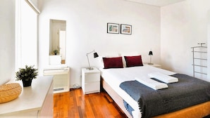 A modern bedroom with a large bed, bedside tables, a mirror, and a small plant. - Downtown River Side by Homing (Lisbon)