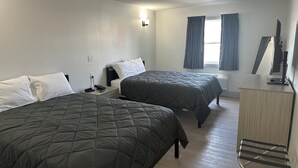 Ett hotellrum med två sängar, ett skrivbord och en TV.