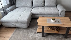 En grå modulsofa med et træbord og et skakspil.