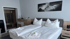 Et moderne hotelværelse med en stor seng, et skrivebord, en stol, et garderobeskab og et maleri på væggen.