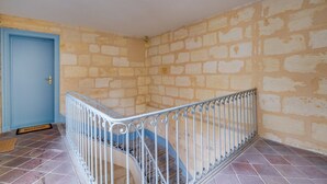 Ein Zimmer mit einer blauen Tür, einer Metalltreppe mit weißer Geländer und einer Steinwand.