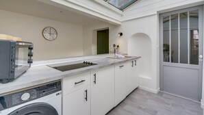 Eine moderne Küche mit Einbauwaschmaschine, einer großen Kochinsel mit Spüle und einem Oberlicht darüber.