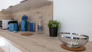 A modern kitchen with a wooden countertop, a stainless steel bowl, a potted plant, a water bottle, and a blue toaster.