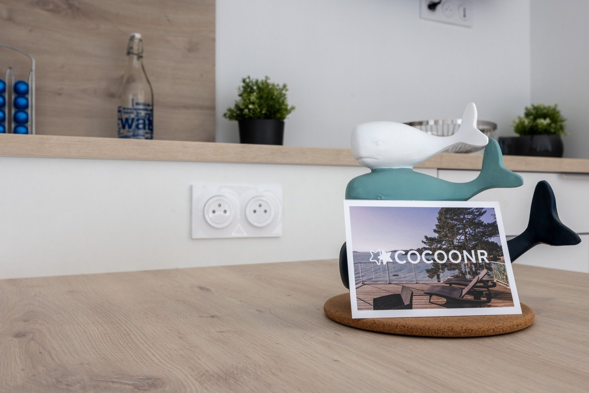 A cork coaster with a photo of a deck and the text "COCOONR".
