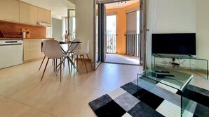 Una sala de estar moderna con una mesa de centro de vidrio, un televisor de pantalla plana y un comedor con sillas y una mesa.