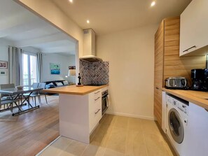 Une cuisine moderne dotée d’un îlot central, d’un lave-linge encastré et d’un coin repas offrant une vue agréable.