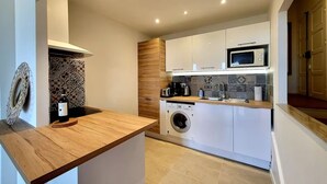 A compact kitchen with a washing machine, microwave, and a wooden countertop. - L'Aiguillon Antibois - Proche Port (Antibes)