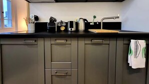 Cocina moderna con armarios grises, encimera negra y ventana que proporciona luz natural.