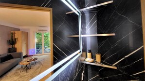 Un salon moderne avec un mur en marbre noir, un canapé en bois, une table basse et une grande fenêtre donnant sur un paysage verdoyant.