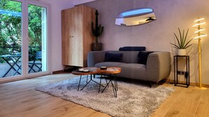 Un salon moderne avec un canapé gris, un meuble en bois, une table basse ronde et un grand miroir au mur.