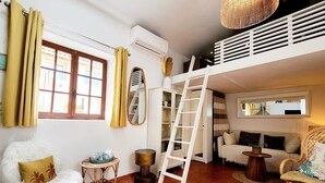 A cozy living room with a white sofa, a fluffy chair, a small round table, a ladder, and a large mirror. - Le Cosy Antibois - Proche Marché Provençal (Antibes)