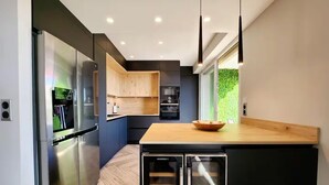 Une cuisine moderne dotée d’un plan de travail en bois, d’appareils électroménagers en acier inoxydable et d’un distributeur d’eau intégré.