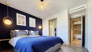 Une chambre moderne avec un grand lit, des murs de couleur sombre et un plancher en bois.