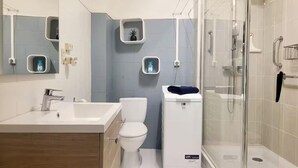 A modern bathroom with a glass shower enclosure, a white sink, and a toilet.