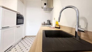 A modern kitchen with white cabinets, a black countertop, and a stainless steel sink.
