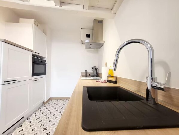 Una cocina moderna con armarios blancos, encimera negra y pileta de acero inoxidable.