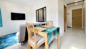 Un comedor con una mesa y sillas de madera, un sofá y un televisor montado en la pared.