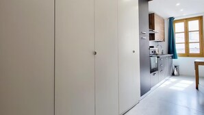 Una cocina moderna con armarios blancos, techo de madera y una ventana con cortinas azules.