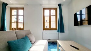 Una habitación moderna con un sofá, una mesa y dos ventanas con cortinas.
