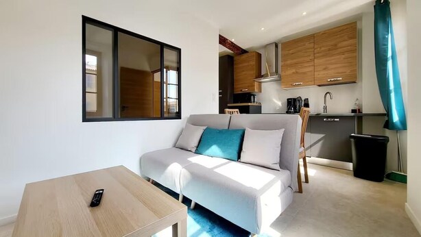 Un salon moderne avec un canapé, une table basse et un coin cuisine à l’arrière-plan.
