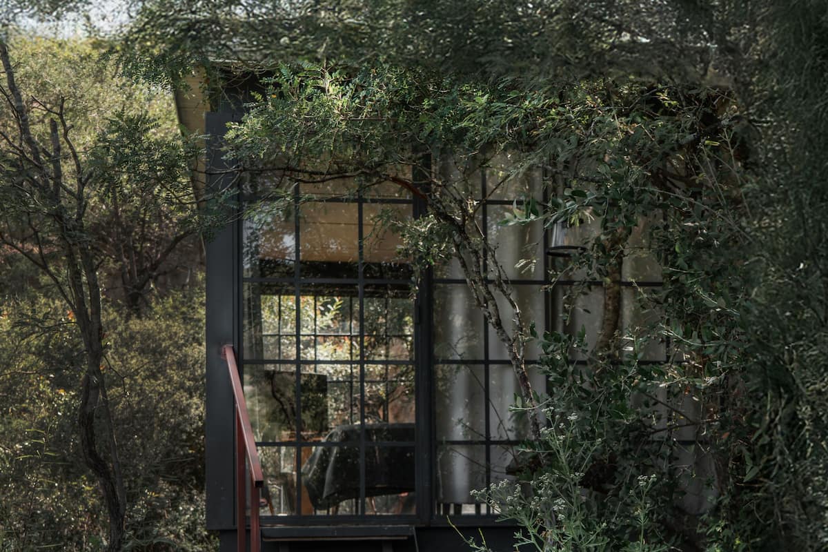 Ein gepflasterter Weg führt zur Villa Santa, umgeben von üppiger Vegetation und einer Metalltreppe.