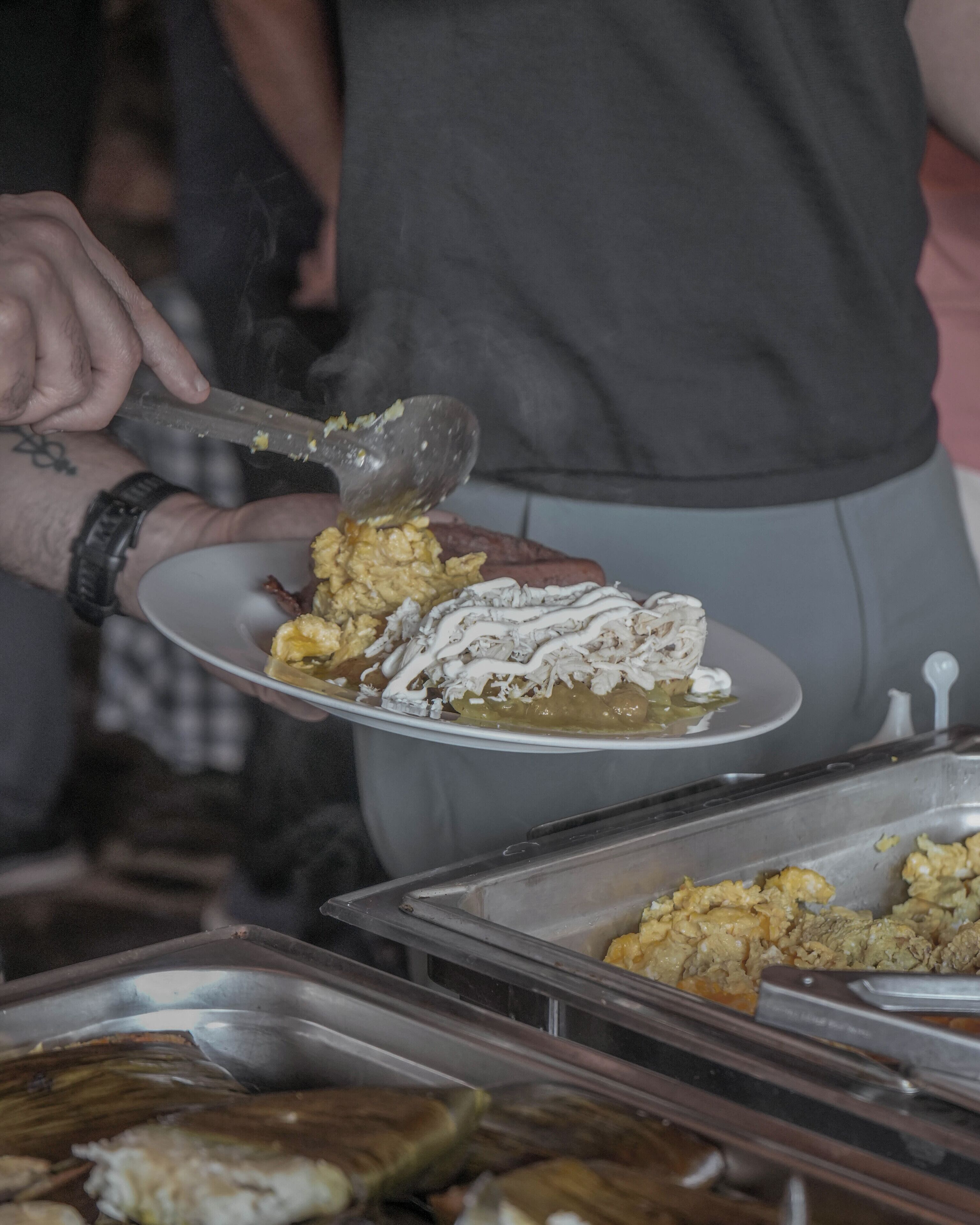 Un buffet proposant divers plats, dont une assiette contenant un plat crémeux blanc, et une personne qui sert la nourriture.