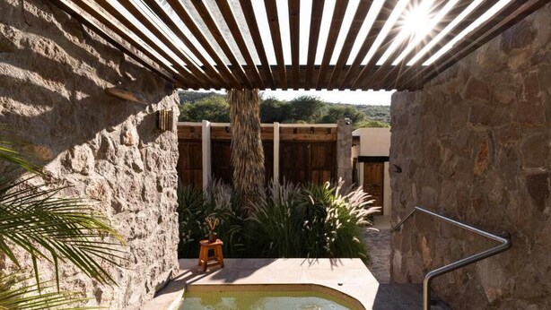A stone-walled outdoor area with a pool, wooden pergola, and plants. - Armadillo Mágico (Armadillo de los Infante)