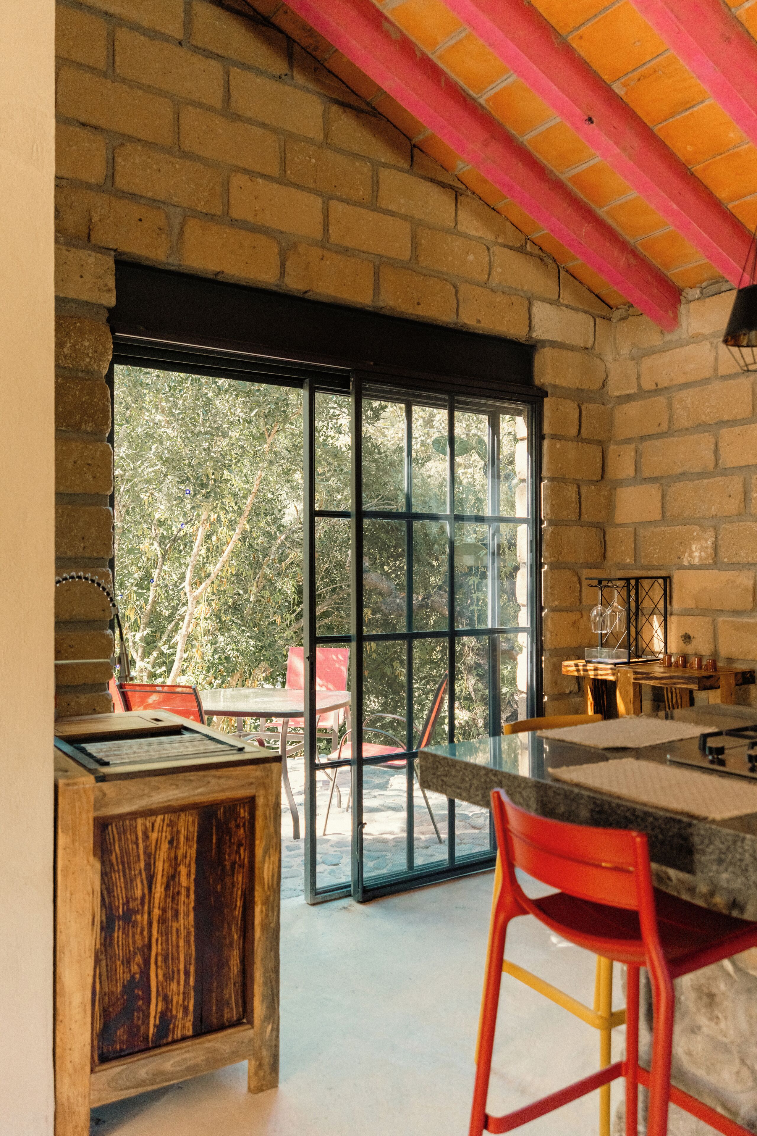 A kitchen with a large window, a brick wall, and a wooden cabinet.