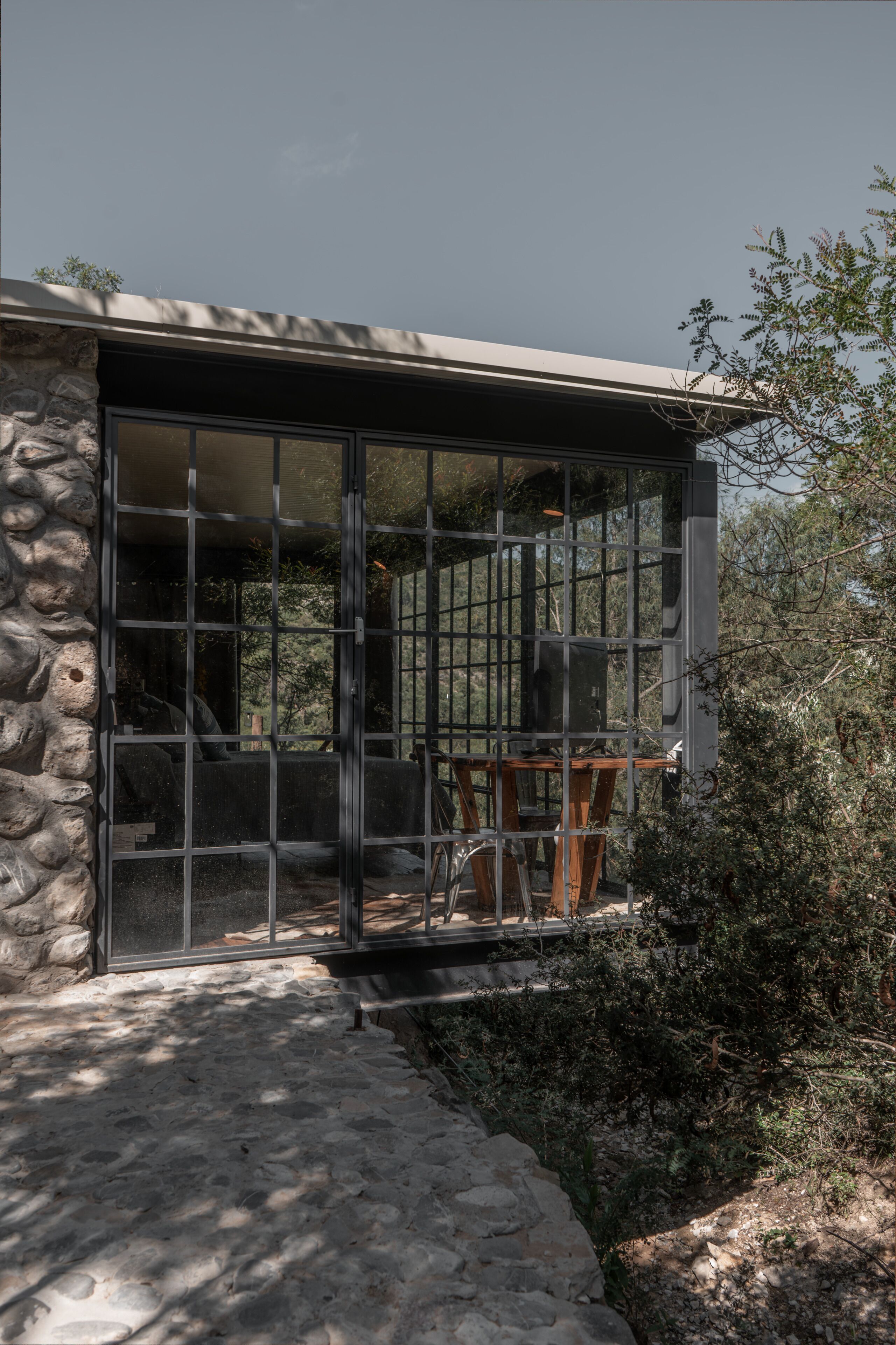 A stone building with a large glass door and a wooden table outside.