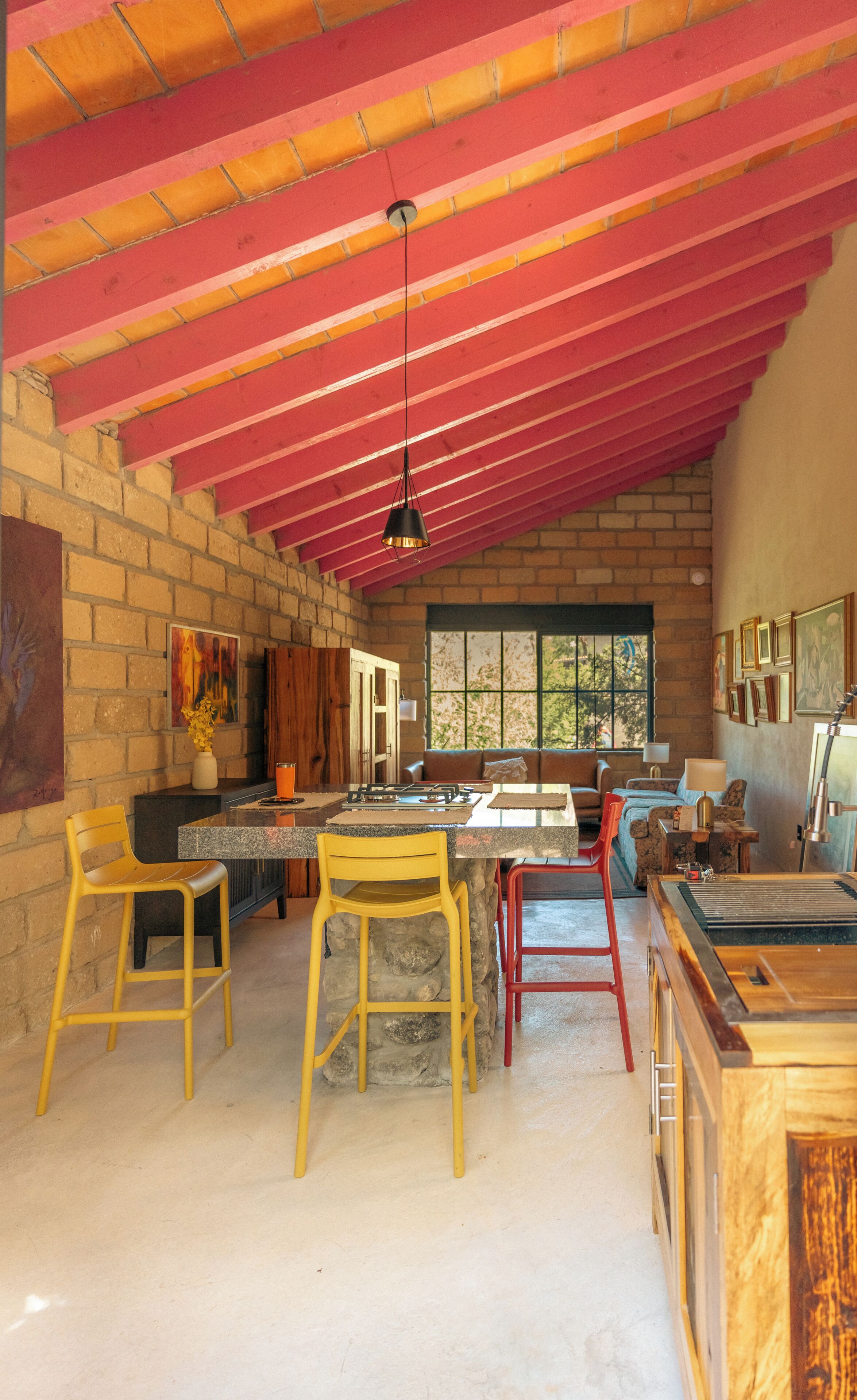 A spacious kitchen with a red ceiling, a dining area with wooden chairs, and a large window providing natural light.