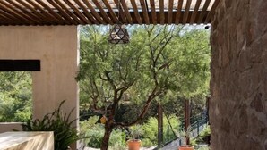 An outdoor patio with a pergola, stone flooring, and potted plants. - Armadillo Mágico (Armadillo de los Infante)