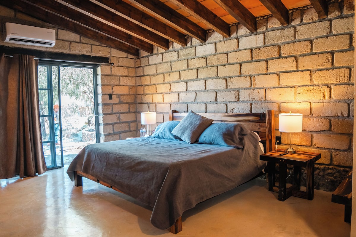 Ein Schlafzimmer mit einem großen Bett, einer Holzbalkendecke und einer Backsteinwand.