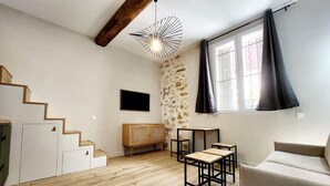 Un vaste espace de vie comprenant un escalier, un mur en pierre, une grande fenêtre avec des rideaux et un luminaire moderne.