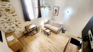 Un salon moderne avec un canapé, une table basse en bois et une table à manger. Un escalier mène à un autre niveau.