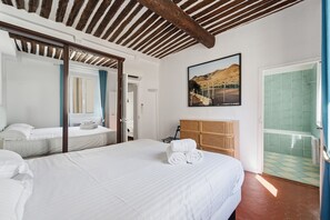 Une chambre d’hôtel avec un lit, une tête de lit en bois, une salle de bain avec une douche carrelée de carreaux verts et un tableau encadré au mur.