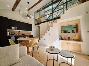A modern kitchen with a dining area, a staircase, and a loft space. - Le Tourraque - Proche Plage (Antibes)