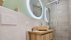 A modern bathroom with a toilet, wooden vanity, and a glass shower enclosure. - Le Championnet - Proche du Port (Antibes)