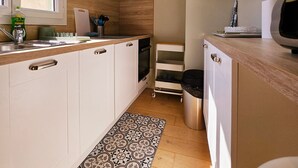 A modern kitchen with white cabinets, a stainless steel sink, a window, and a patterned floor runner. - Le Delmas Riviera - Duplex dans Vieil Antibes (Antibes)