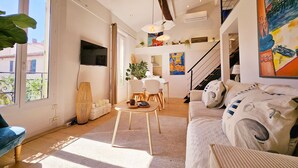 A spacious living room with a large window, a staircase, and a dining area. - Le Delmas Riviera - Duplex dans Vieil Antibes (Antibes)