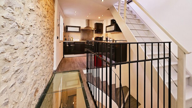 A modern kitchen with a built-in stove, a microwave, and a range hood. There is a glass railing overlooking a lower level.