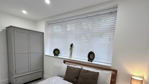 Une chambre à coucher comprenant un lit, une armoire, une fenêtre avec des stores et une lampe de chevet.