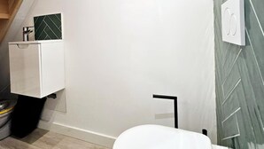 A modern bathroom with a white toilet, a small white cabinet, and a green herringbone-patterned wall.