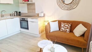 A modern kitchen with white cabinets, a built-in oven, and a coffee machine.
